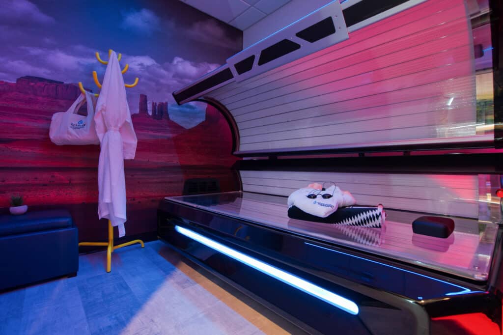 Client beside a full-body red light therapy bed with red ambient lighting